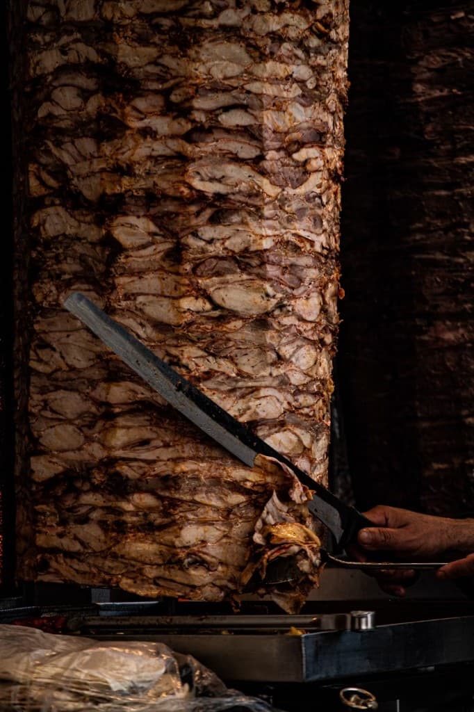 Broche de kebab : un couteau racle la viande grillée.
